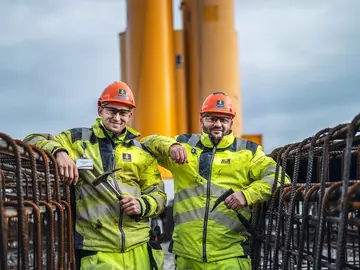 Zwei Bauer Mitarbeiter mit gelben Jacken zwischen einem Stahlkorb für die Schlitzwand in Krsko.